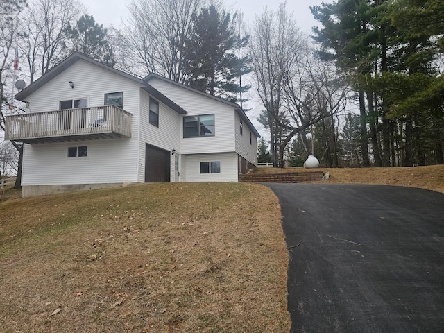 view of property exterior featuring a balcony, driveway, and an attached garage
