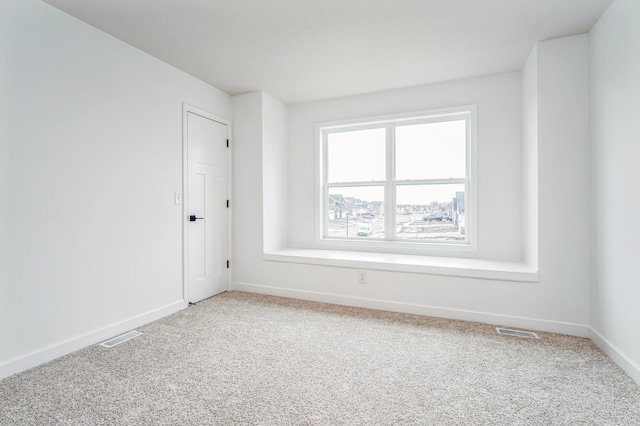 spare room with visible vents, baseboards, and light carpet