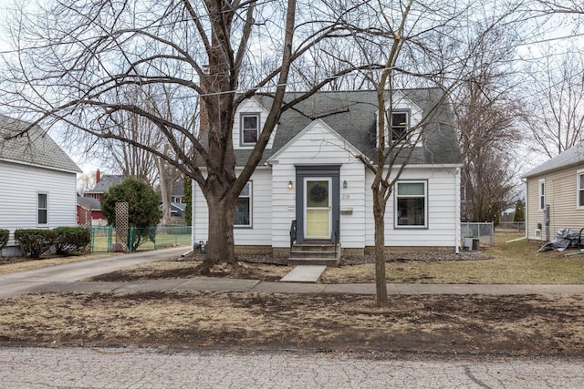 new england style home with a shingled roof, entry steps, and fence