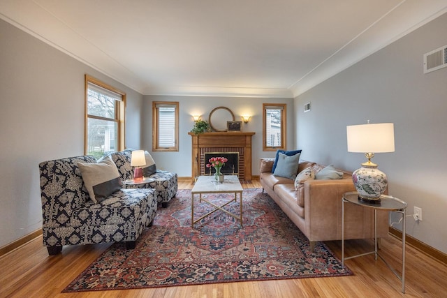 living area featuring visible vents, crown molding, and wood finished floors