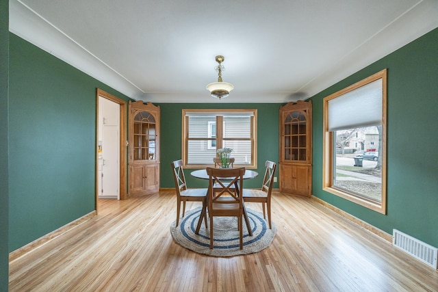 dining area with light wood finished floors, a wealth of natural light, visible vents, and baseboards