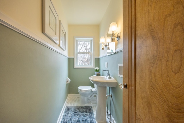 half bathroom with toilet, a sink, tile patterned floors, and baseboards