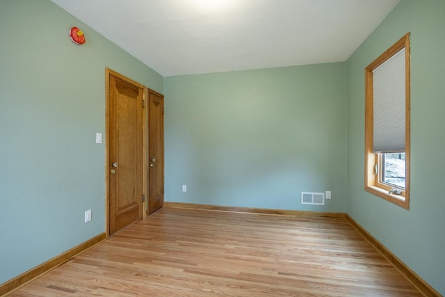 unfurnished room featuring light wood-style flooring, baseboards, and visible vents