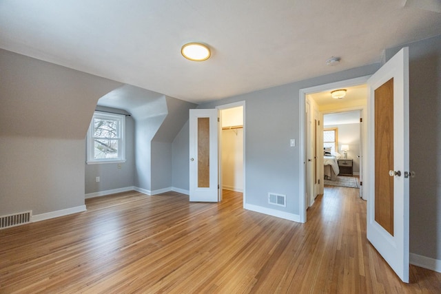 additional living space with light wood finished floors, baseboards, and visible vents