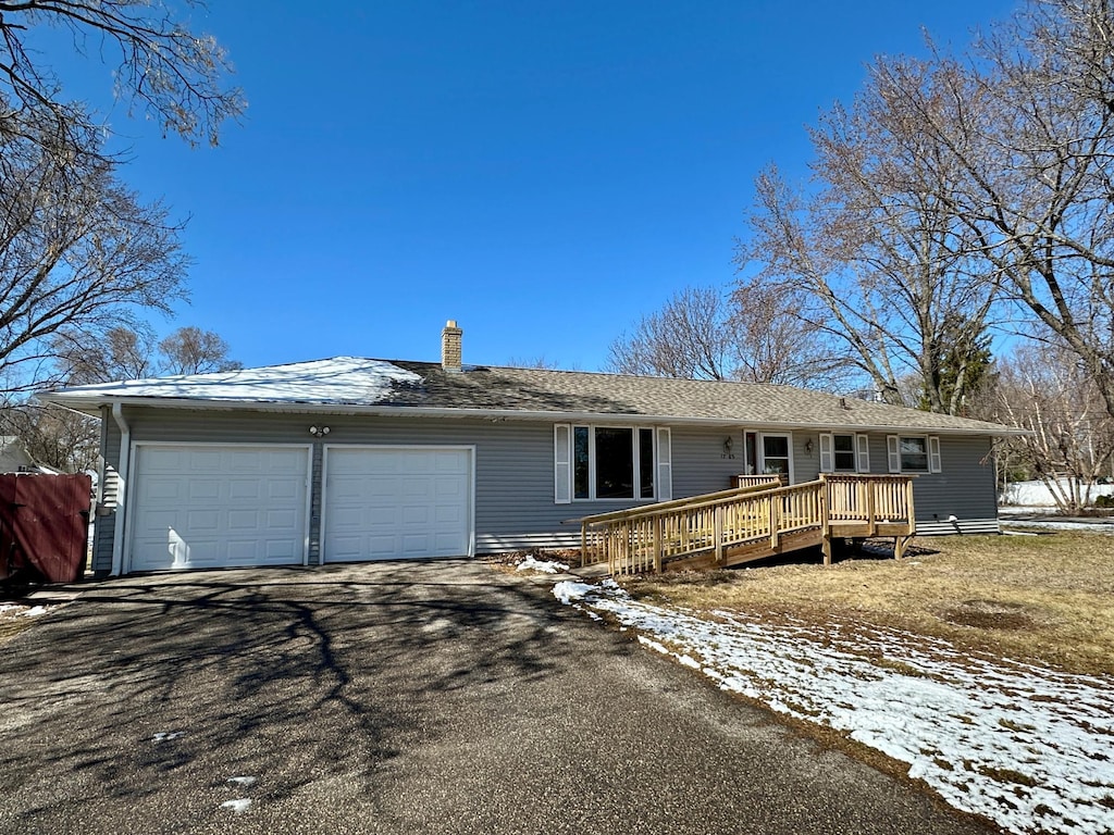 ranch-style house featuring a chimney, a garage, and aphalt driveway