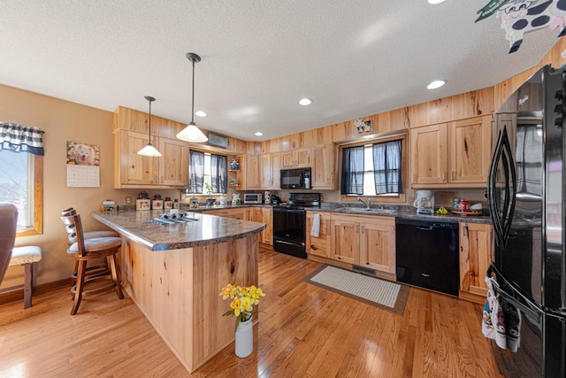 19023 Davis Ave, Faribault, MN 55021 - kitchen with a peninsula, light wood finished floors, light brown cabinetry, a sink, and black appliances