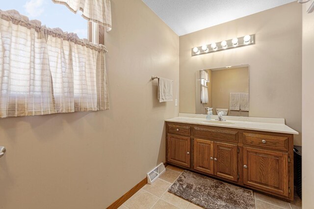 19023 Davis Ave, Faribault, MN 55021 - bathroom featuring baseboards, visible vents, tile patterned floors, vanity, and vaulted ceiling