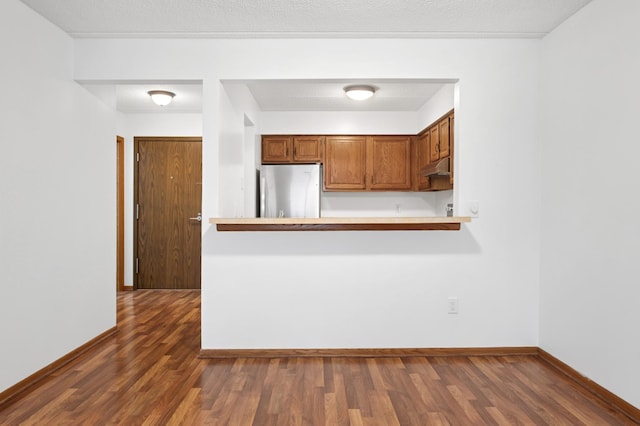 3300 Louisiana Ave S Unit 523, Saint Louis Park, MN 55426 - kitchen with freestanding refrigerator, under cabinet range hood, dark wood-type flooring, brown cabinets, and light countertops