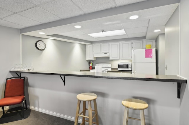 3300 Louisiana Ave S Unit 523, Saint Louis Park, MN 55426 - kitchen with white appliances, under cabinet range hood, a paneled ceiling, a kitchen bar, and recessed lighting