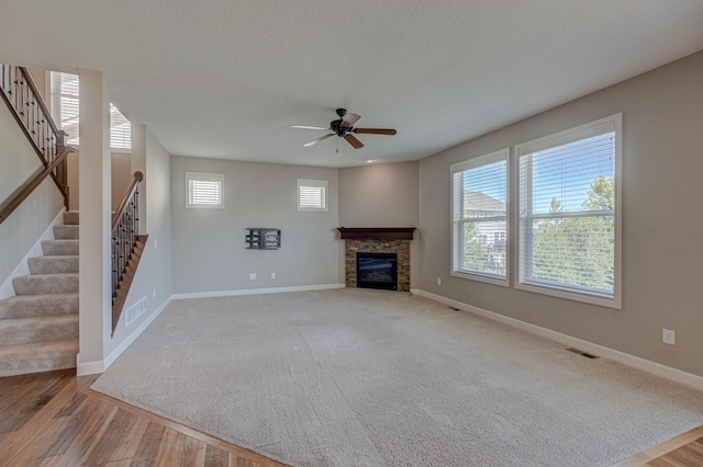 4764 Ashton Curv, Woodbury, MN 55129 - unfurnished living room featuring stairway, a ceiling fan, a fireplace, light wood-style floors, and a textured ceiling