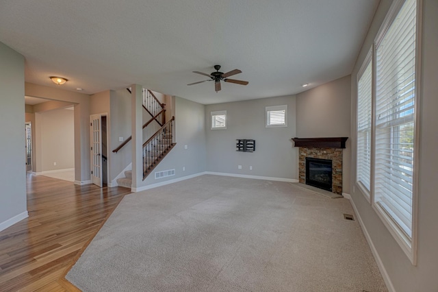 4764 Ashton Curv, Woodbury, MN 55129 - unfurnished living room featuring a ceiling fan, a stone fireplace, stairway, and light wood-style floors