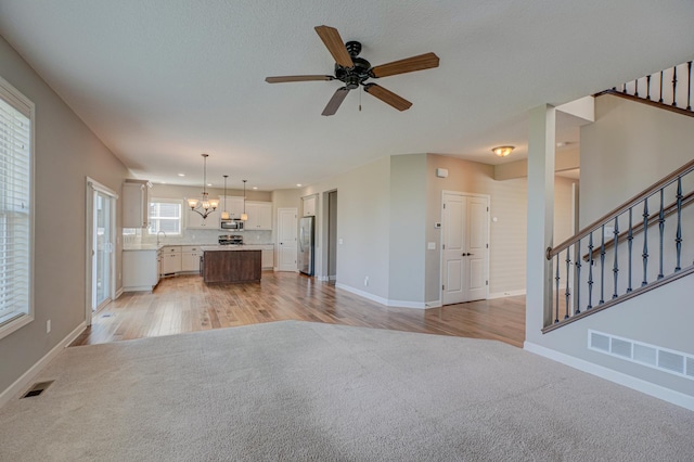 4764 Ashton Curv, Woodbury, MN 55129 - unfurnished living room featuring light carpet, ceiling fan, stairway, a chandelier, and recessed lighting