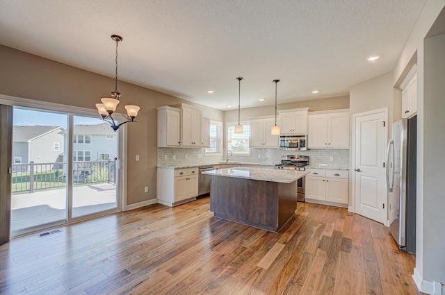 4764 Ashton Curv, Woodbury, MN 55129 - kitchen featuring stainless steel appliances, decorative backsplash, a chandelier, light wood-style floors, and recessed lighting