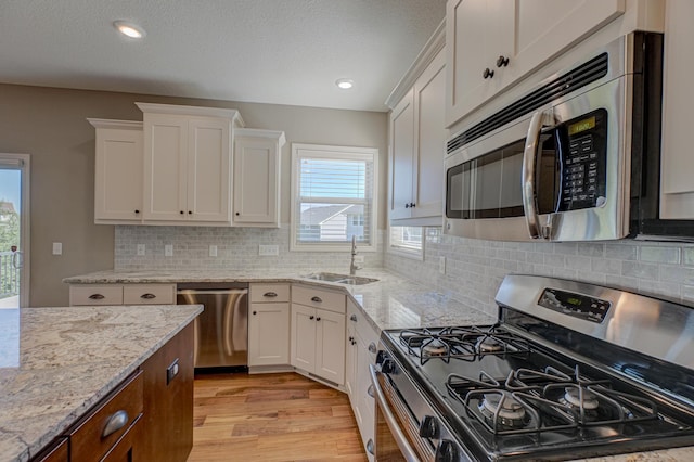 4764 Ashton Curv, Woodbury, MN 55129 - kitchen with stainless steel appliances, white cabinets, light wood finished floors, light stone countertops, and recessed lighting