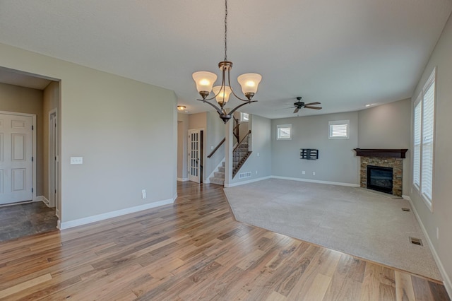 4764 Ashton Curv, Woodbury, MN 55129 - unfurnished living room featuring ceiling fan, light wood-style floors, stairs, a fireplace, and a chandelier