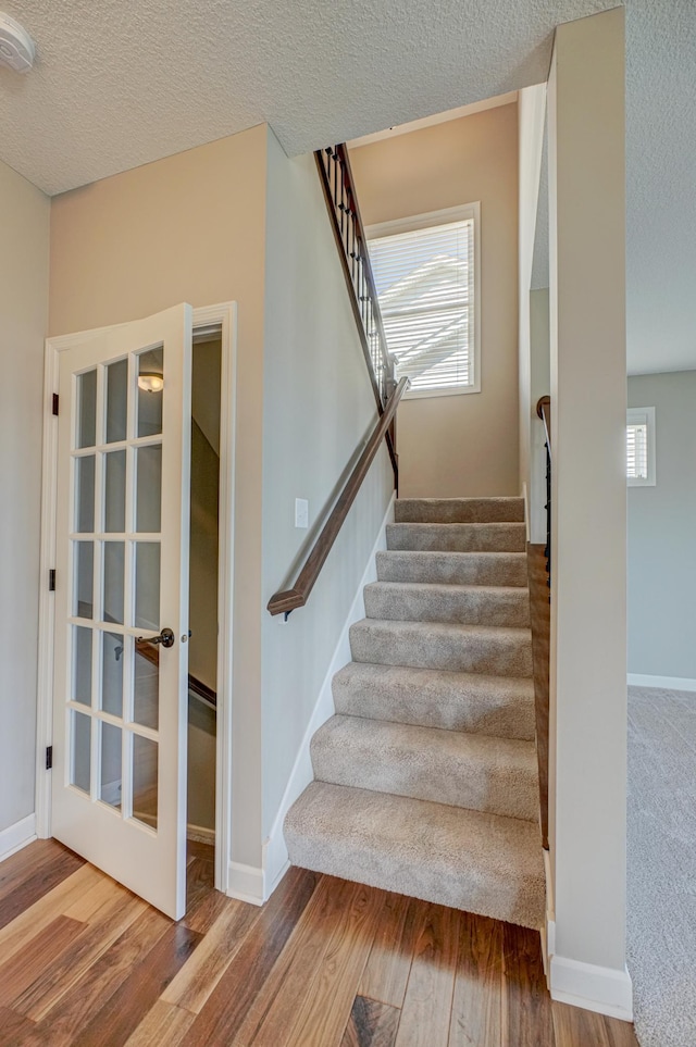 4764 Ashton Curv, Woodbury, MN 55129 - stairway with wood finished floors, plenty of natural light, a textured ceiling, and french doors