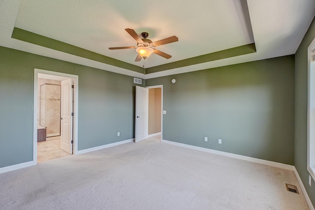 4764 Ashton Curv, Woodbury, MN 55129 - unfurnished bedroom with light carpet, a tray ceiling, connected bathroom, and a ceiling fan