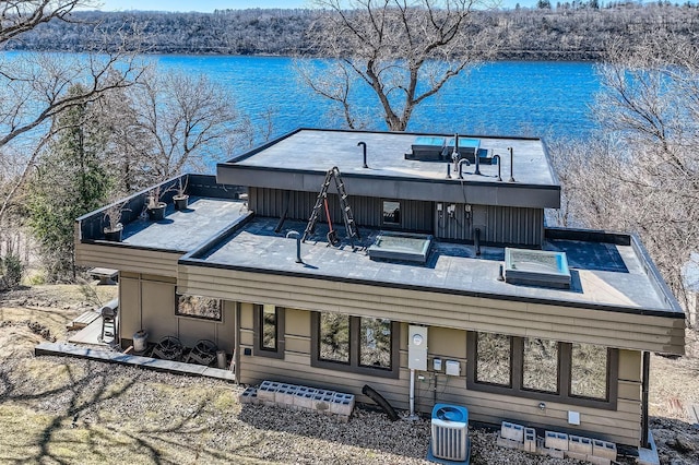 rear view of property with central AC, a water view, and a hot tub