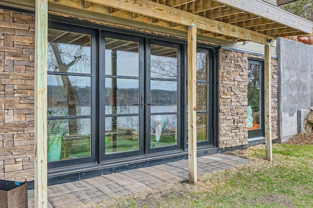 view of exterior entry with a water view and stone siding