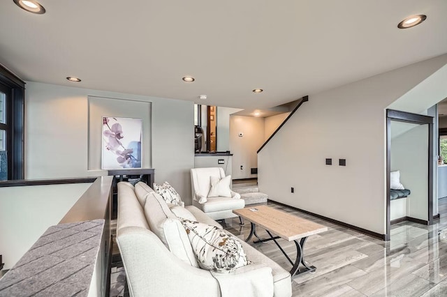 living room featuring baseboards, stairway, and recessed lighting