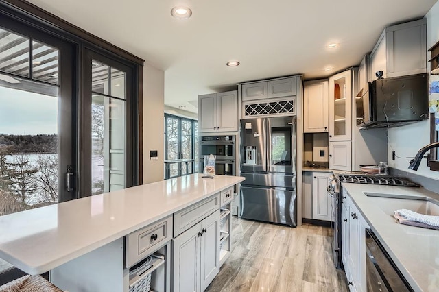 kitchen with stainless steel appliances, gray cabinetry, light wood-style floors, and light countertops