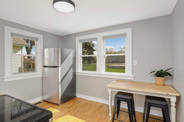 dining area featuring baseboards, light wood-type flooring, and a wealth of natural light