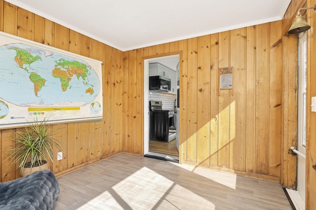 living area with baseboards, ornamental molding, wood finished floors, and wooden walls