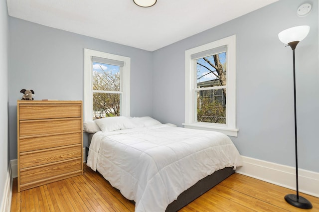 bedroom with light wood-style floors, baseboards, and multiple windows