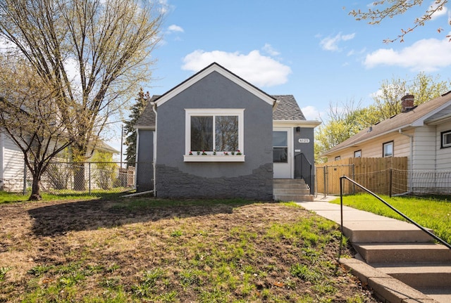 bungalow-style home featuring fence, a front yard, and stucco siding