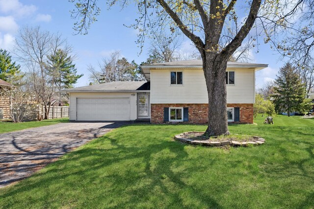 split level home featuring a garage, fence, a front yard, and aphalt driveway