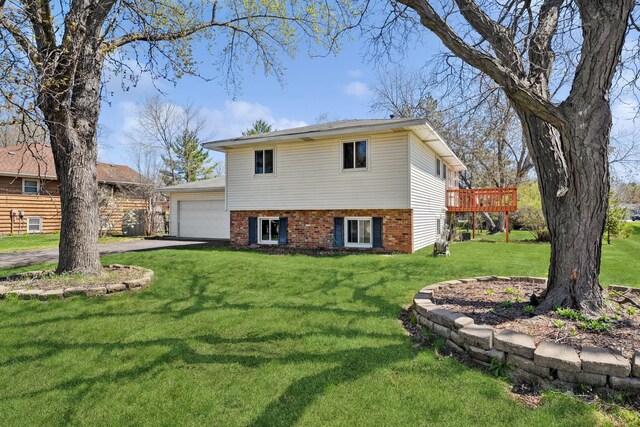 view of front of home featuring a front lawn, brick siding, a garage, aphalt driveway, and a wooden deck