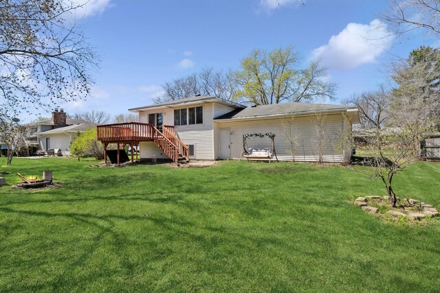 back of property featuring a lawn, a deck, a fire pit, and stairs