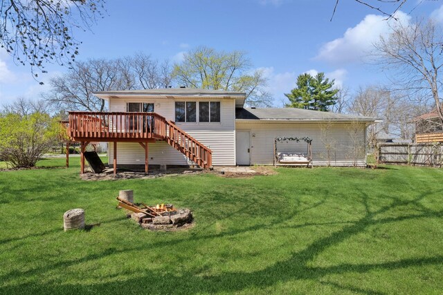 back of property featuring fence, an outdoor fire pit, a deck, stairway, and a lawn