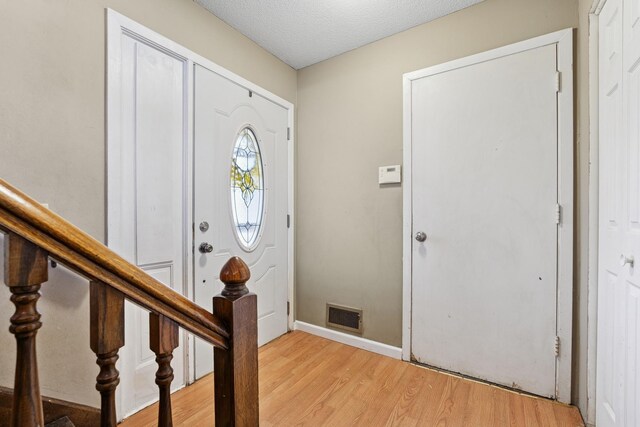 entrance foyer with visible vents, a textured ceiling, baseboards, and light wood-type flooring