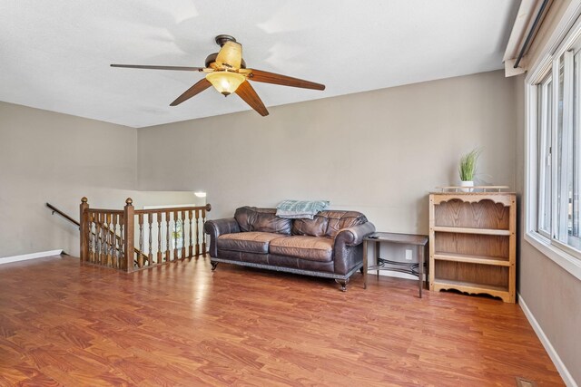 sitting room featuring baseboards, ceiling fan, wood finished floors, and an upstairs landing