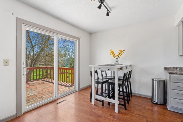 dining space featuring visible vents, a textured ceiling, wood finished floors, and track lighting