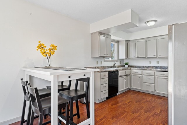 kitchen with freestanding refrigerator, dark wood-style flooring, black dishwasher, a sink, and gray cabinetry