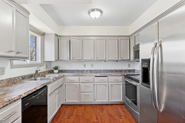 kitchen with light countertops, a sink, dark wood-style floors, and stainless steel appliances