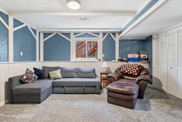 carpeted living room featuring wainscoting and beam ceiling