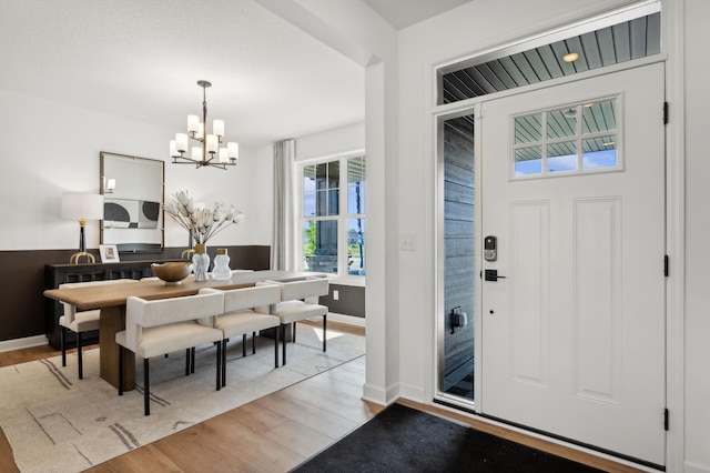 entryway featuring baseboards, an inviting chandelier, and wood finished floors