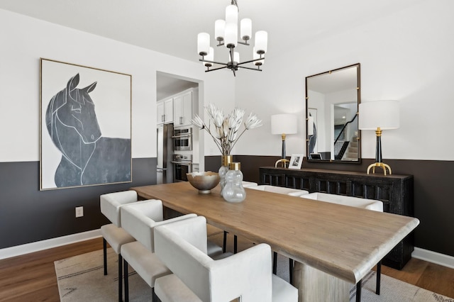 dining space featuring baseboards, wood finished floors, and a notable chandelier