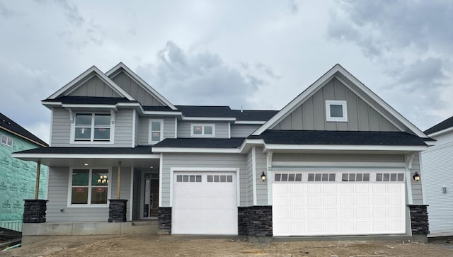 craftsman house with a porch, an attached garage, board and batten siding, and stone siding