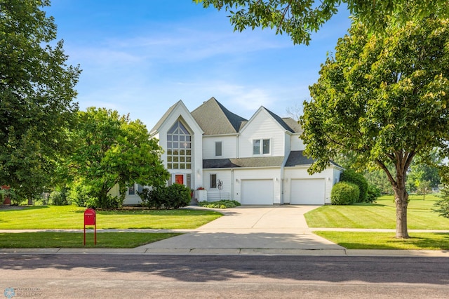 traditional home featuring roof with shingles, driveway, an attached garage, and a front lawn