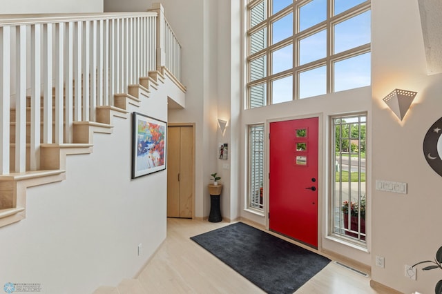 entryway featuring a high ceiling, visible vents, stairs, and wood finished floors