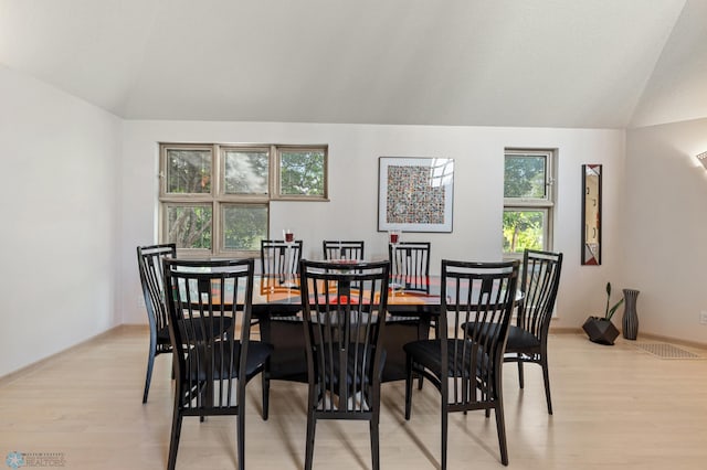 dining space featuring light wood-style flooring and vaulted ceiling