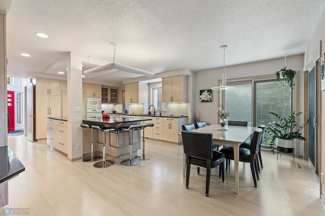 dining area featuring a textured ceiling, light wood-style flooring, and recessed lighting