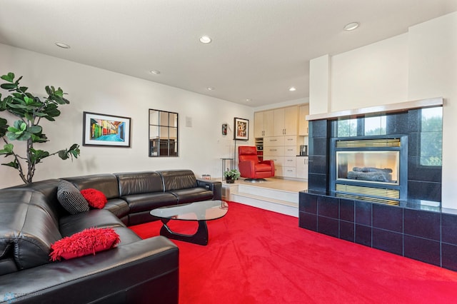 living area with carpet floors, recessed lighting, and a tiled fireplace