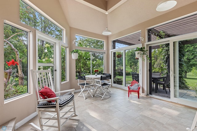 sunroom / solarium featuring baseboards and a towering ceiling