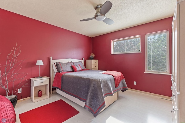 bedroom featuring baseboards, ceiling fan, and a textured ceiling