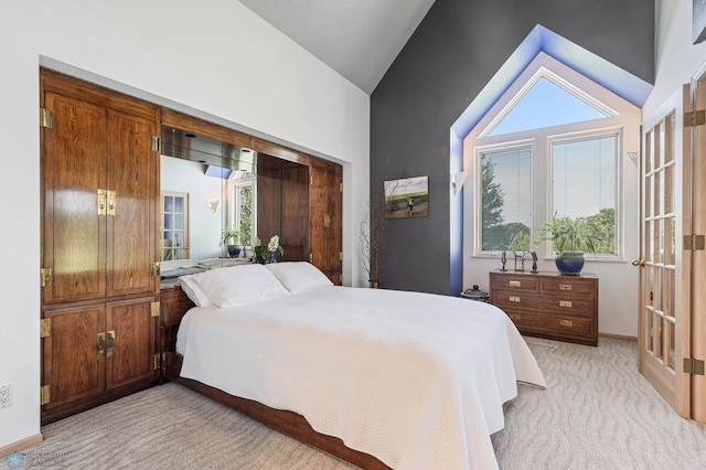 bedroom featuring baseboards, high vaulted ceiling, and light carpet